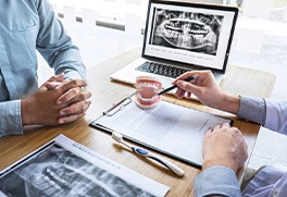 a dentist showing a patient a model of a mouth