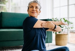 a woman stretching her arms while sitting in a living room
