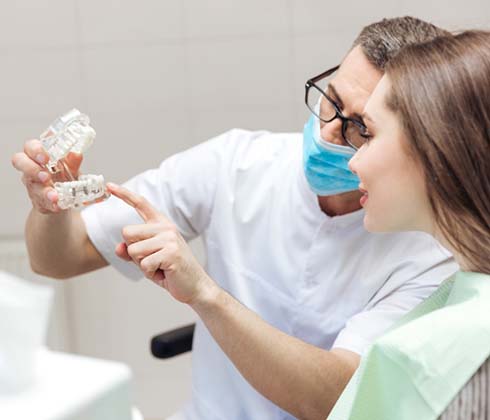 Dentist showing patient model dental implants in Cleburne 