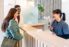 a patient speaking with front desk staff at a dental office
