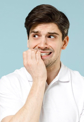 Man biting his fingers on blue background