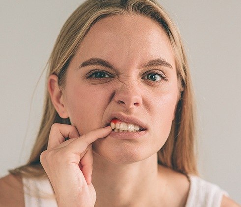 Woman in need of periodontal therapy pointing to red gums
