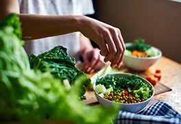 A hand grabbing healthy veggies from a bowl