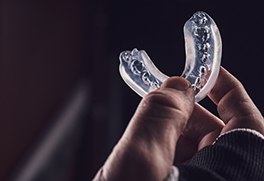 A closeup of a hand holding a clear mouthguard