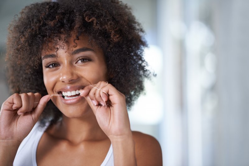 closeup of young woman flossing teeth 