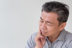 Senior man struggling with problems of ill-fitting dentures