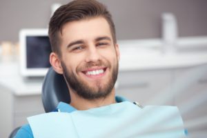 Smiling man in a blue shirt after getting dental implants 