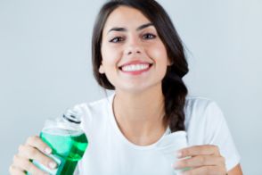 Smiling woman using mouthwash