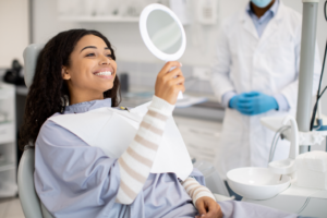 a woman looking in a mirror sitting in a dental chair